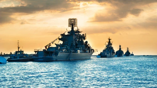 Military navy ships in a sea bay at sunset time