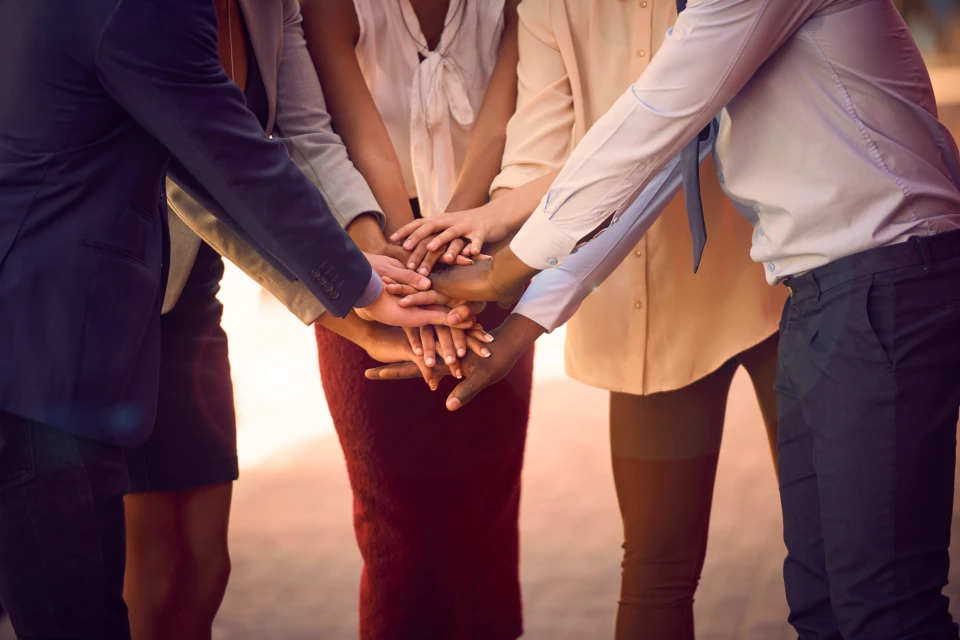 Group of people placing hands together in middle of circle