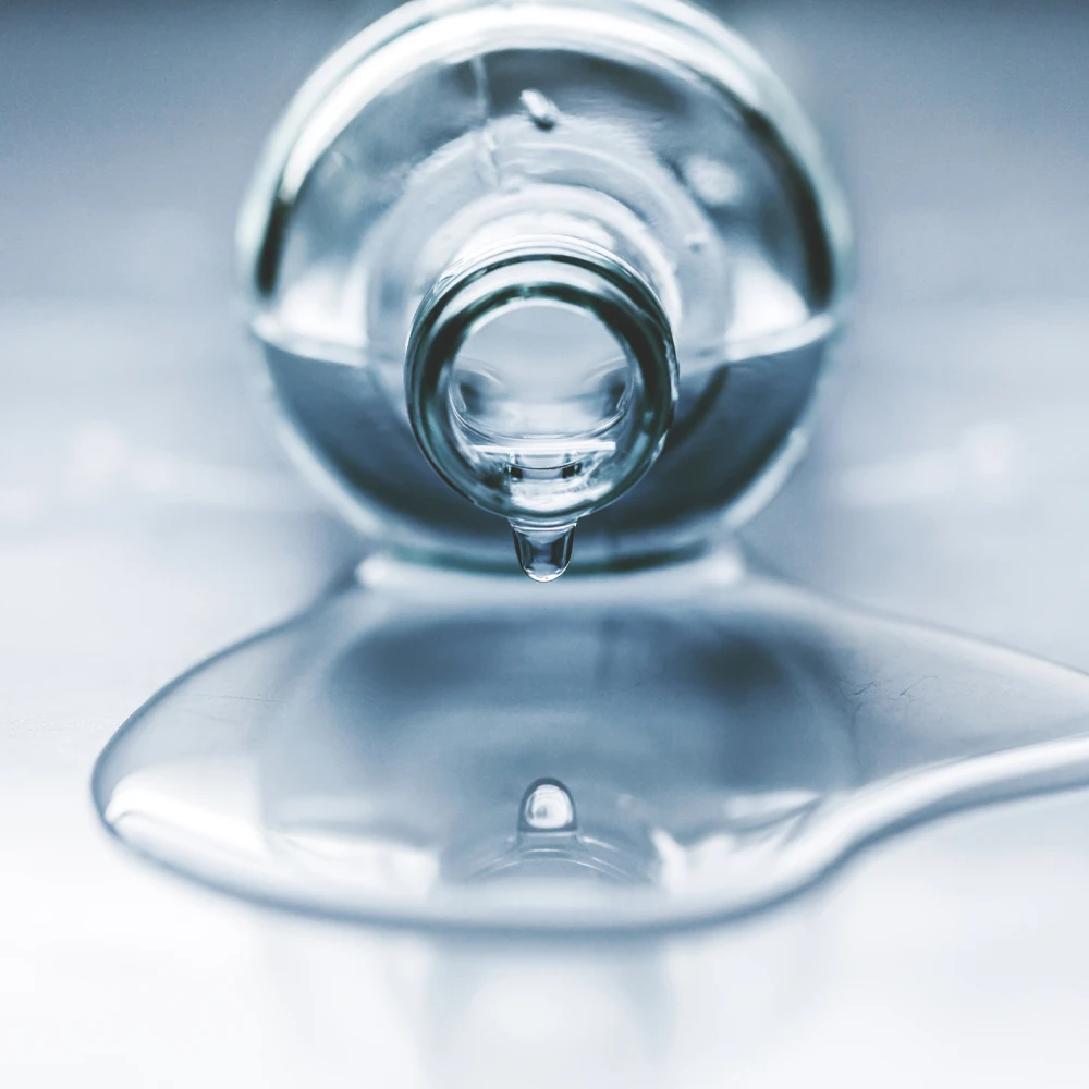 Beautiful image of one drop and its reflection. Bottle full of water, lying on the table. Water is spilled. Water drips.
