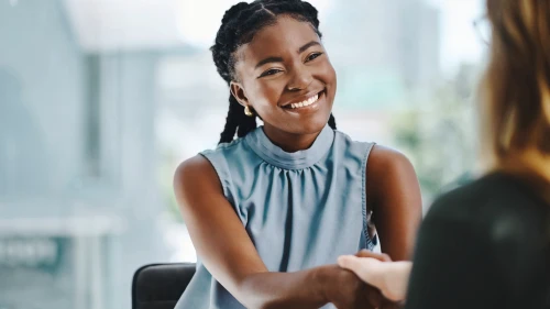Confident young african businesswoman shaking hands with a colleague in an office