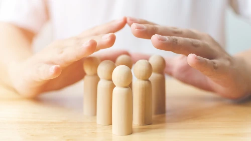 Protection people health and insurance concept. Hand shield protect wooden human on table