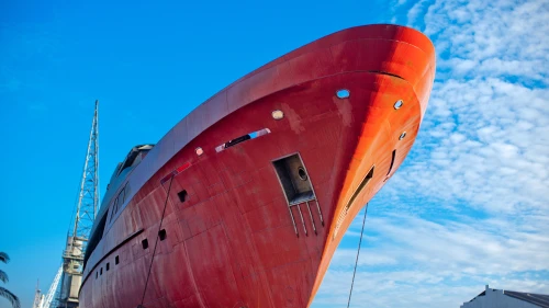 Vivid red ship against blue sky on dry land for repairs.
