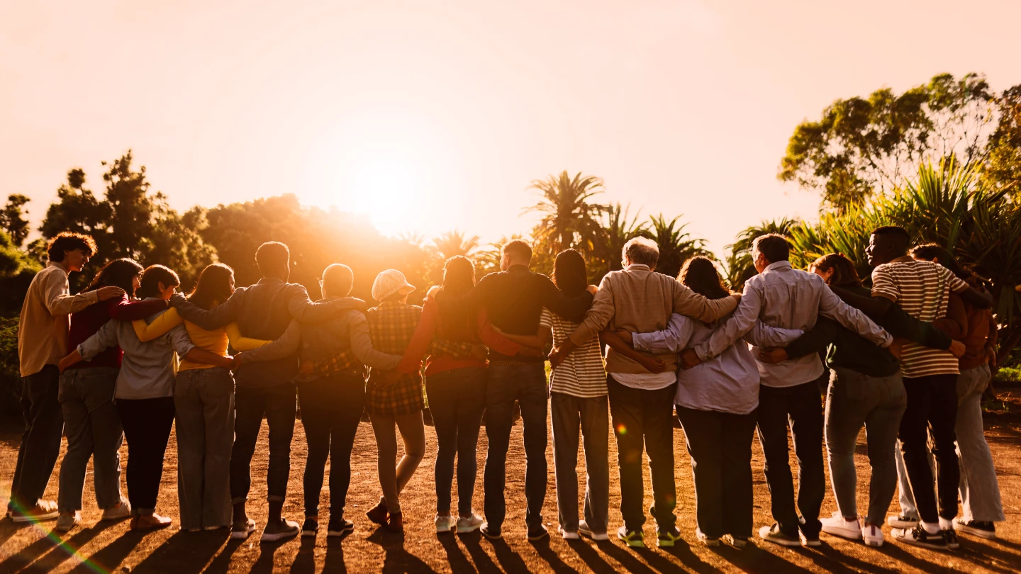 Group of people embraced facing sunset