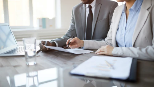 Cropped image of unrecognizable business people signing contract during meeting in office, focus on female hand holding pen, copy space