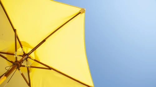 A bright yellow umbrella used besides the pool or on the beach. It catches the sun and is brightly coloured. Taken in Lagos, Portugal.